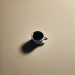 A minimalist image featuring a simple white coffee cup filled with black coffee, placed on a soft, muted beige background. The clean lines and serene contrast between the dark coffee and light background create a calm, modern aesthetic with no additional objects or distractions.